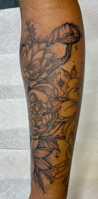 a black and white tattoo of flowers on a person's leg